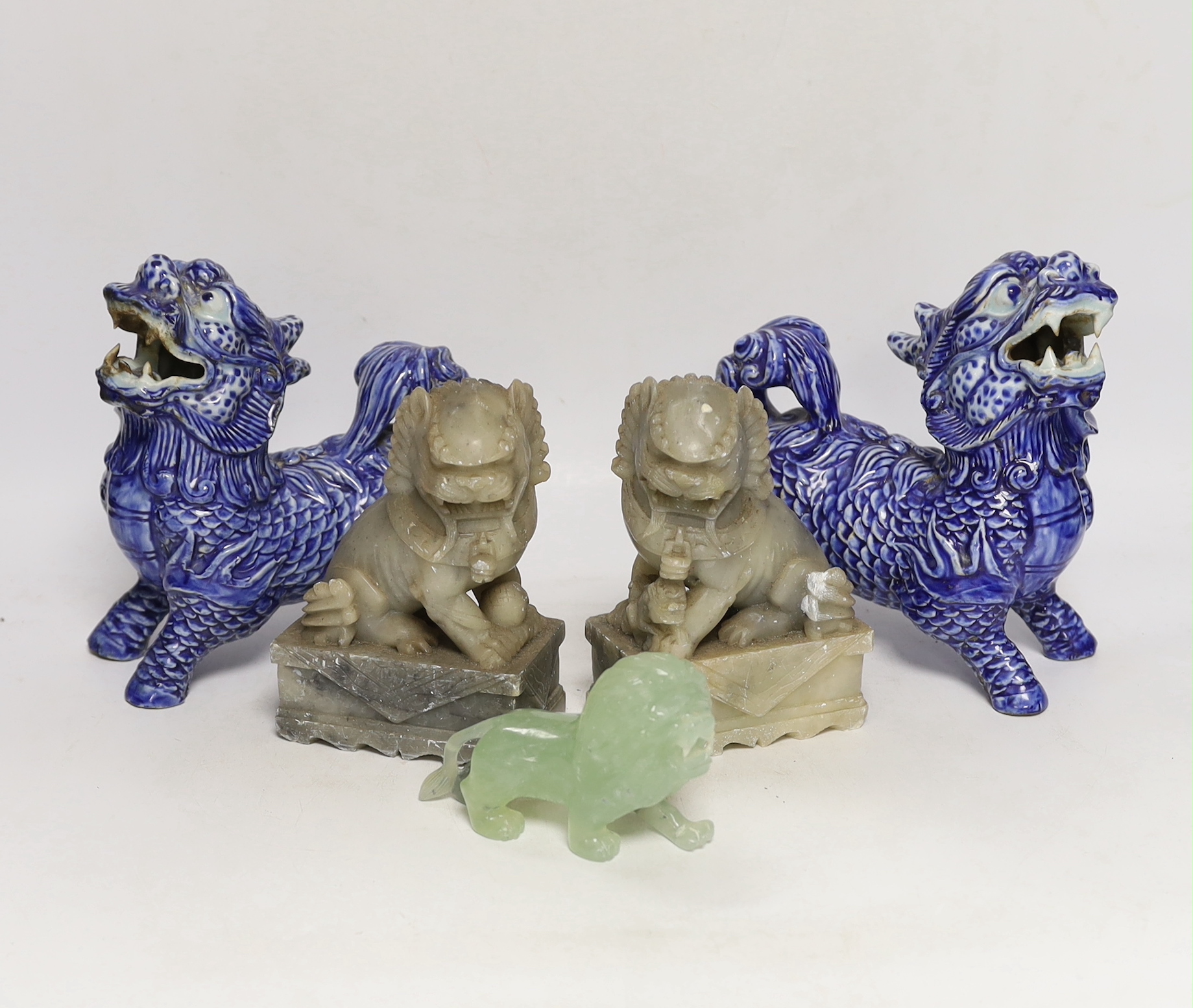 Two pairs of Chinese lion dogs; a blue and white porcelain set and a carved soapstone set, together with a carved jade lion, tallest 18cm (5)